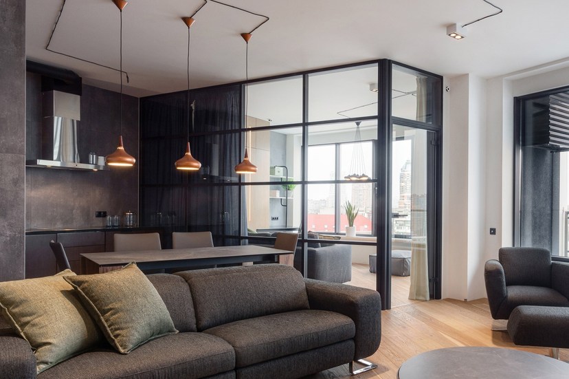 Salón moderno dividido por una elegante mampara de cristal con perfil negro.